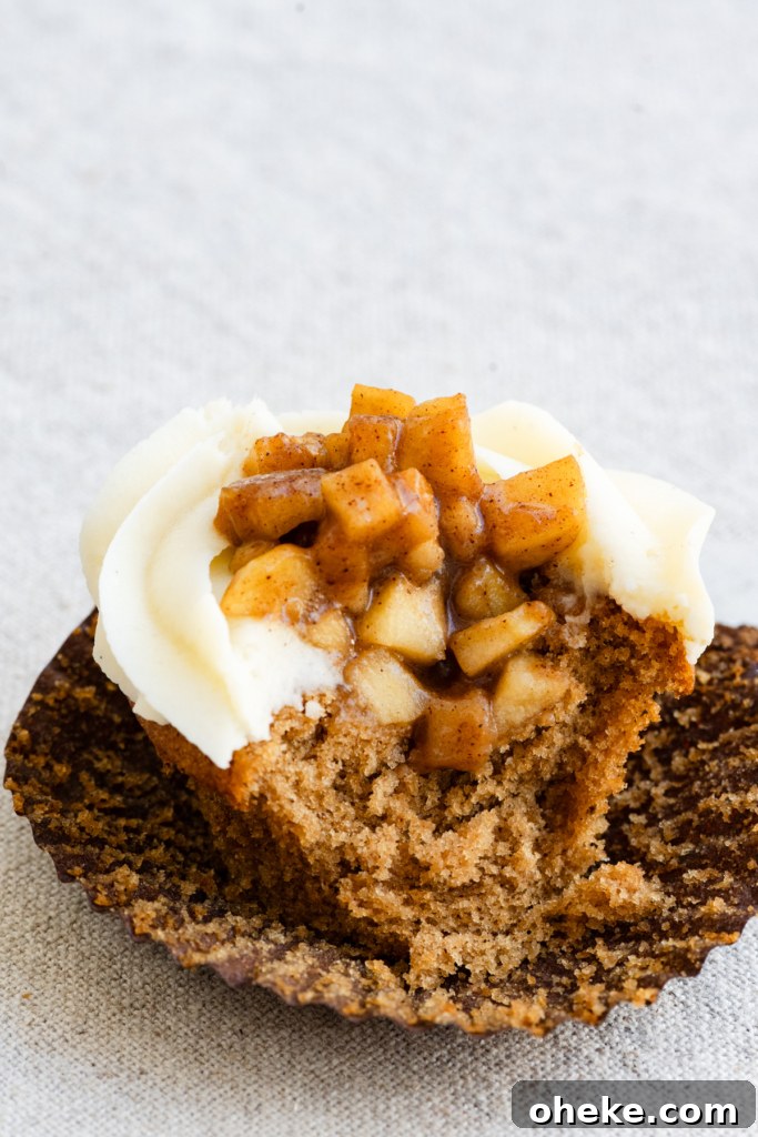 Apple Pie Cupcakes Recipe with Cinnamon Streusel 5 Cupcake with a center of apple pie filling topped with vanilla frosting bitten in half.