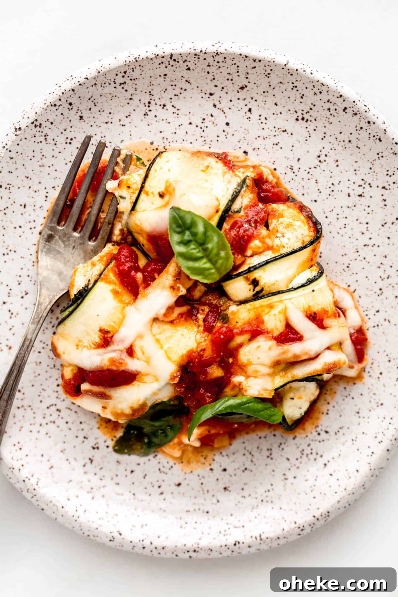 Ricotta-Stuffed Zucchini Involtini with Parmesan and Herbs 10 Zucchini involtini on a white speckled plate