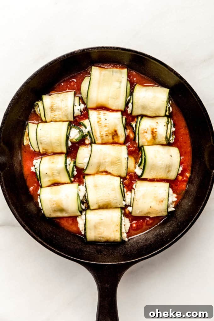 Ricotta-Stuffed Zucchini Involtini with Parmesan and Herbs 7 zucchini roll ups on tomato sauce in a cast iron skillet
