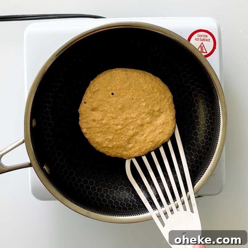 Peanut Butter Banana Protein Pancakes with Cottage Cheese Filling 7 Flipping over a pancake in a frying pan.