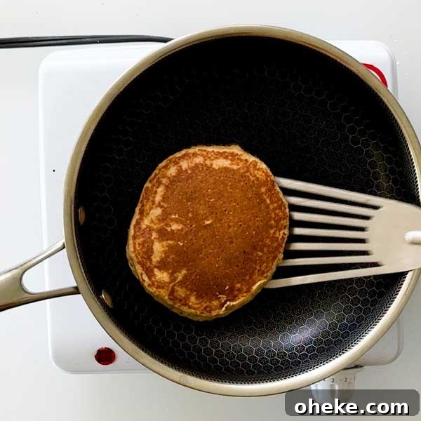 Peanut Butter Banana Protein Pancakes with Cottage Cheese Filling 8 Flipping over a pancake in a frying pan.
