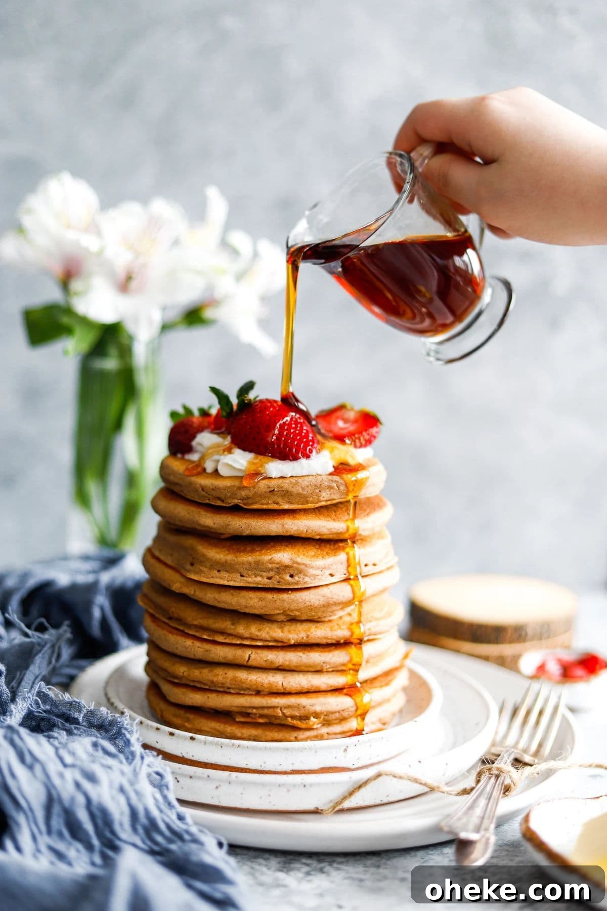 A tall stack of Old-Fashioned Pancakes with syrup poured on the top.