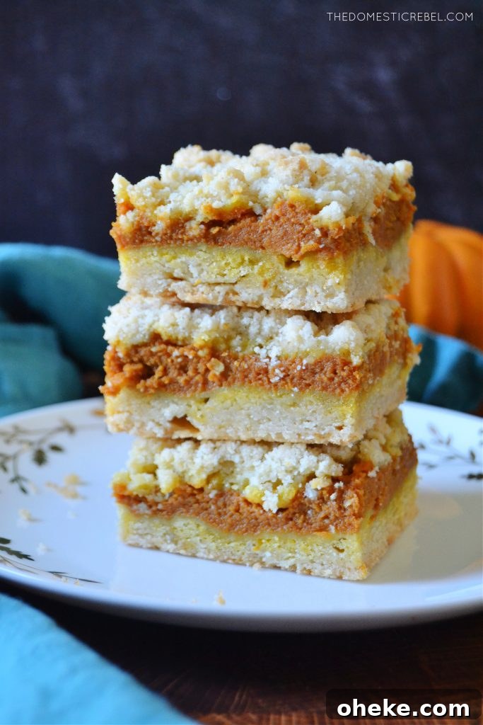Pumpkin Pie Crumble Bars Recipe — Fall Dessert Bars 3 a trio stack of pumpkin pie crumble bars on a white plate