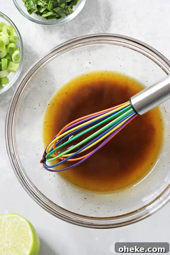 A glass bowl filled with honey lime chipotle dressing with a whisk in the bowl.