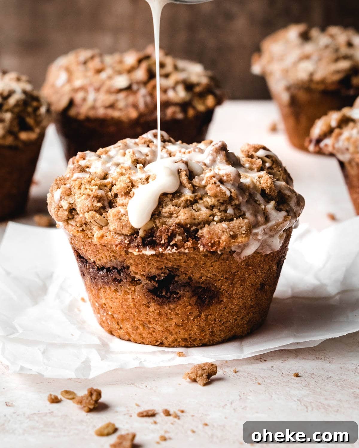 Moist Cinnamon Streusel Muffins Recipe for Perfect Breakfast 2 Glaze being drizzled over cinnamon streusel muffins in a muffin tin.