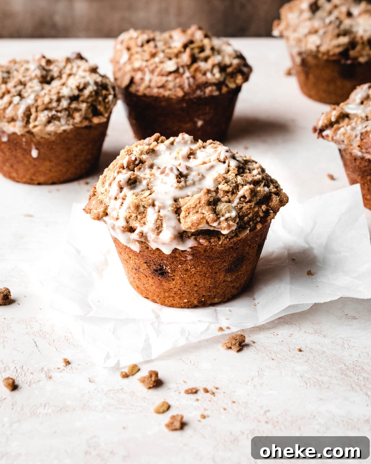 Moist Cinnamon Streusel Muffins Recipe for Perfect Breakfast 7 Several cinnamon streusel muffins on parchment paper covered with glaze.