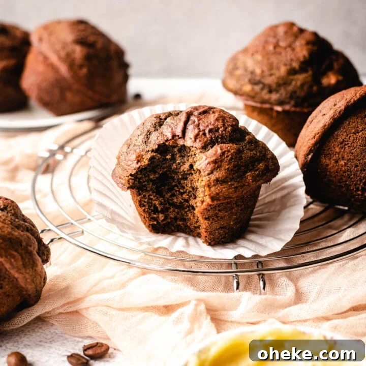 Large coffee muffin with a big bite taken out of it sitting on top of a paper muffin liner.