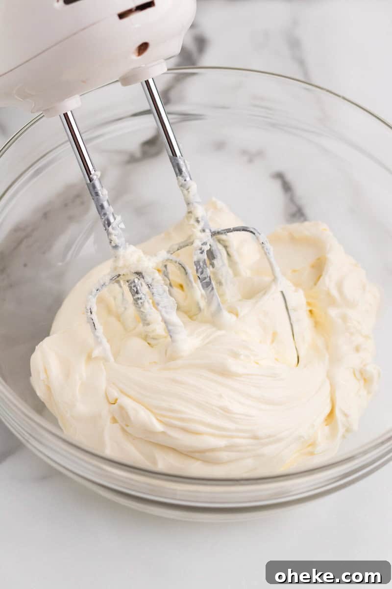 using a hand mixer to mix together the cheesecake dip.