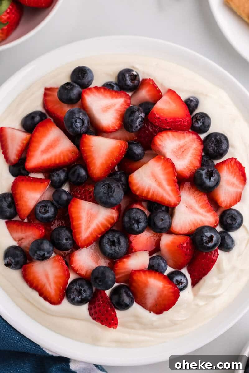 adding the strawberries and blueberries to the Patriotic Cheesecake Dip.