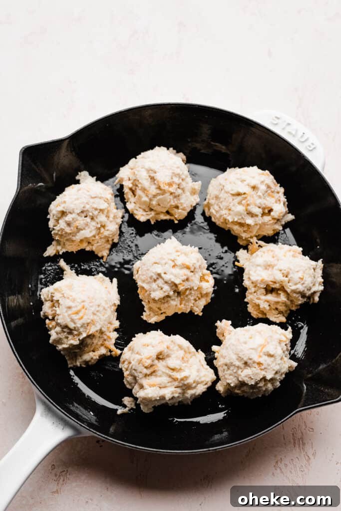 Dough dropped into rounds in a skillet. 