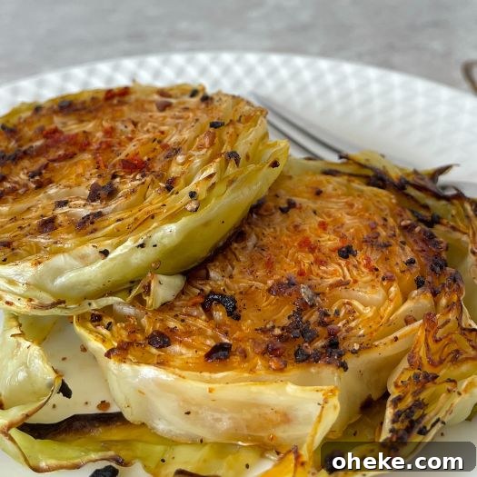 Crispy Roasted Cabbage Steaks with Garlic and Parmesan 2 Cabbage steaks on a white plate on counter
