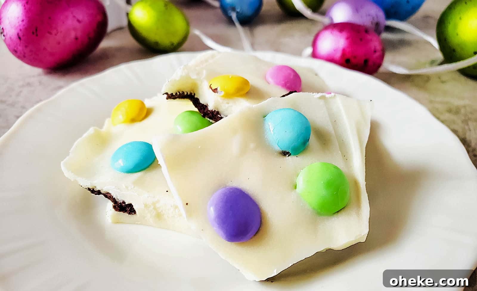 Easter chocolate bark on a white plate with colorful easter eggs.