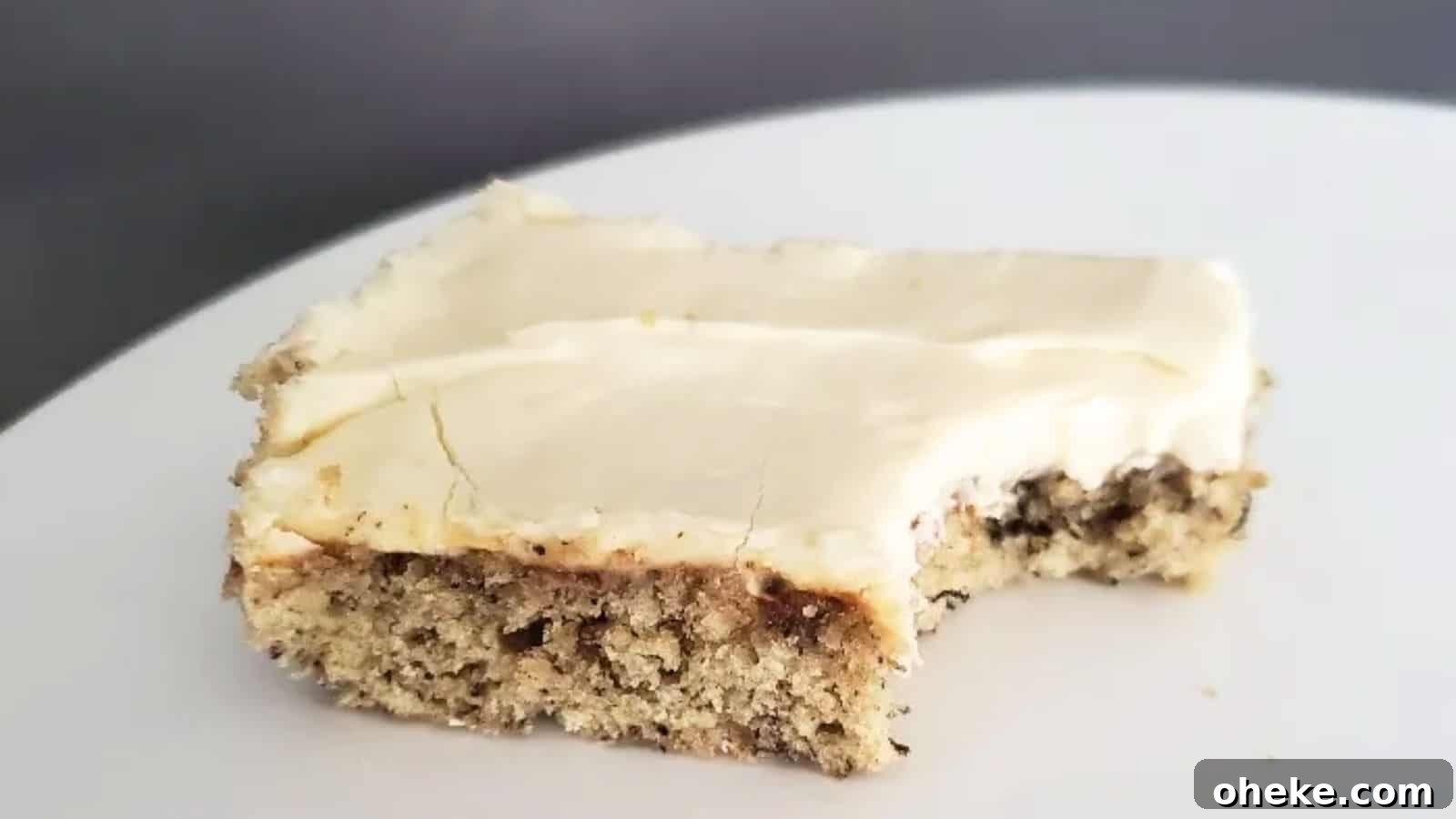 Image shows a Frosted Banana Bar with a bite taken from it on a white plate.