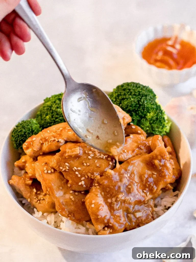 spoon drizzling honey garlic sauce on honey garlic chicken stir fry with steamed broccoli and rice