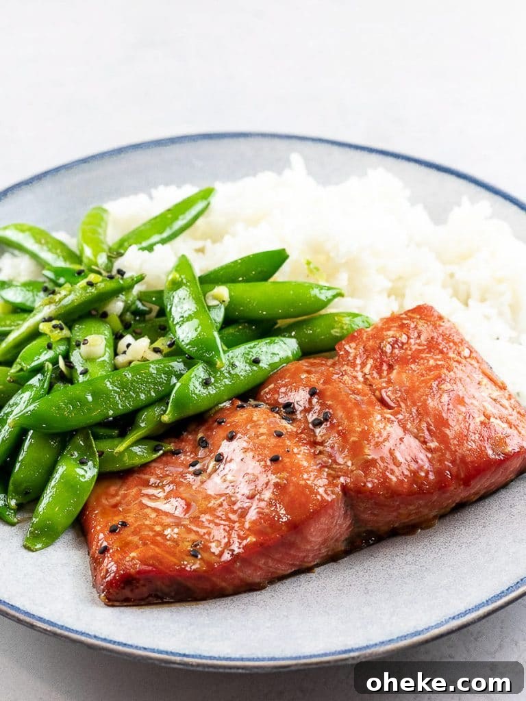 Baked teriyaki salmon with sugar snap peas and rice on a blue plate