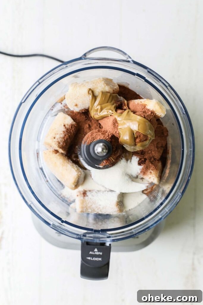 Thick Dreamy Chocolate Smoothie Bowl Recipe for Breakfast 5 Frozen bananas, cacao powder, and sunbutter shown in a food processor.