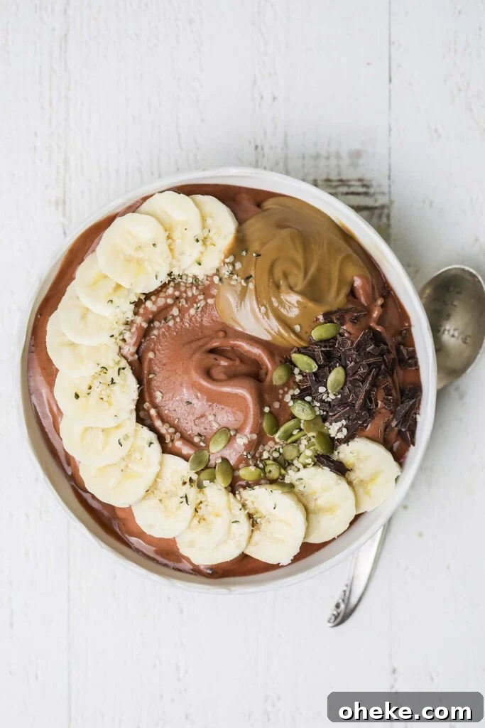 Thick Dreamy Chocolate Smoothie Bowl Recipe for Breakfast 8 A chocolate smoothie in a bowl topped with banana, nut butter, and seeds.