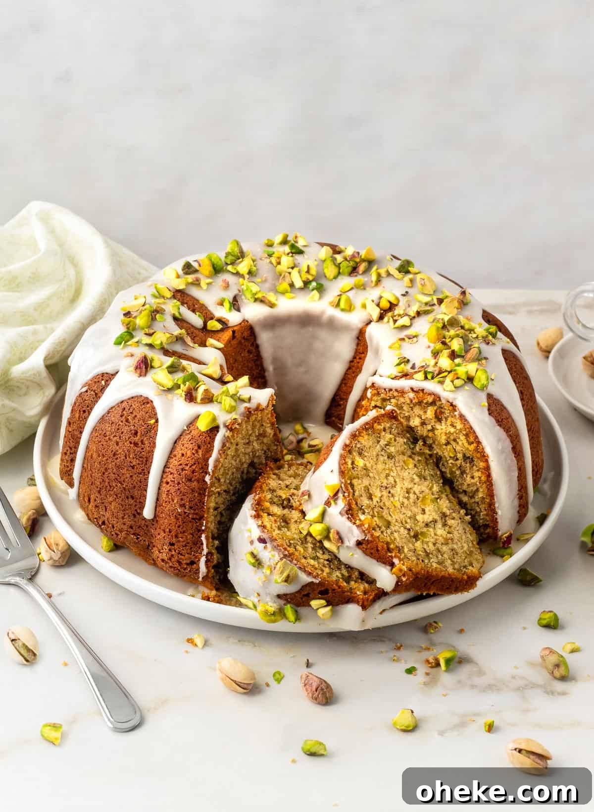 Pistachio bundt cake with two slices cut on platter.