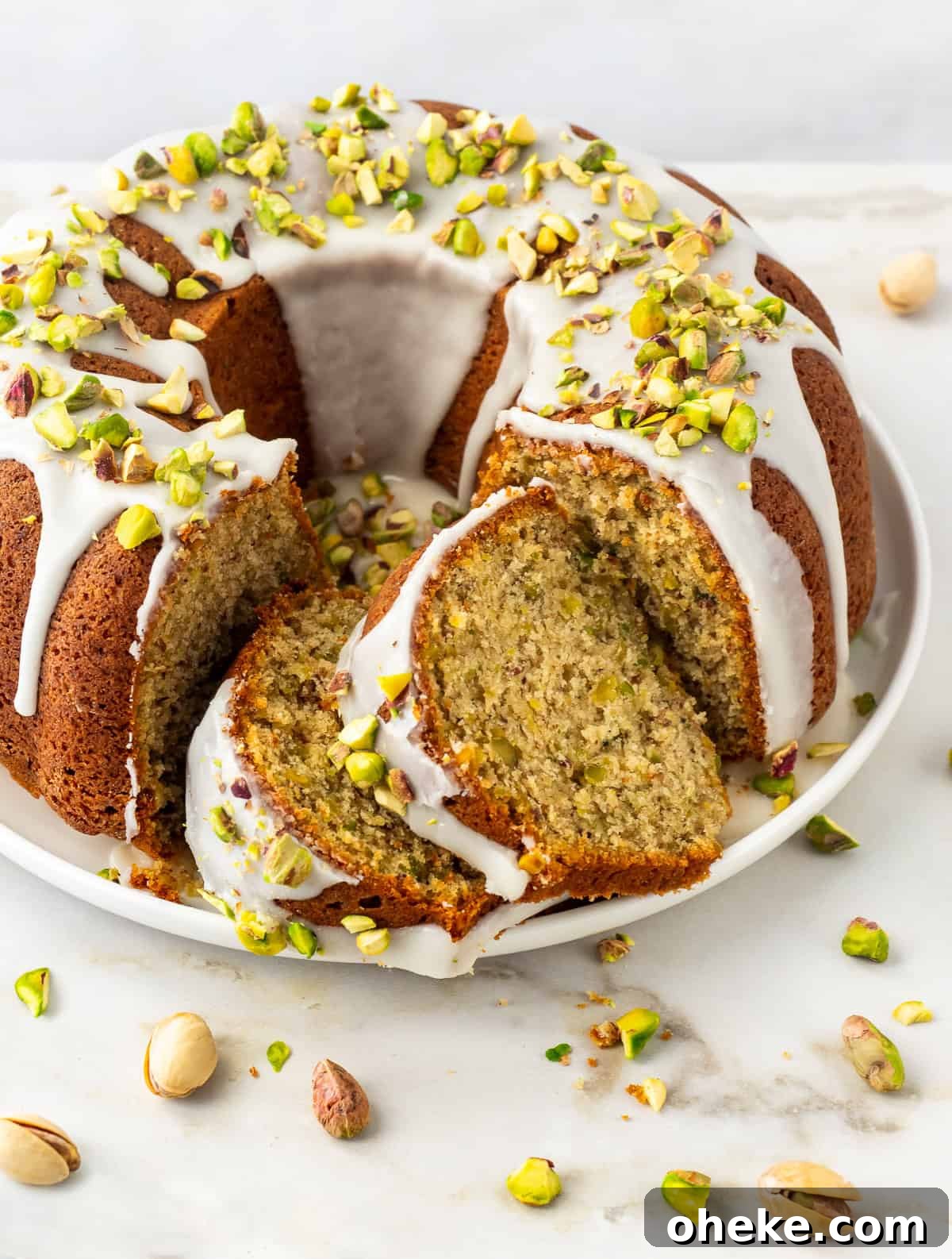 Close-up of a pistachio bundt cake drizzled with glaze on platter.