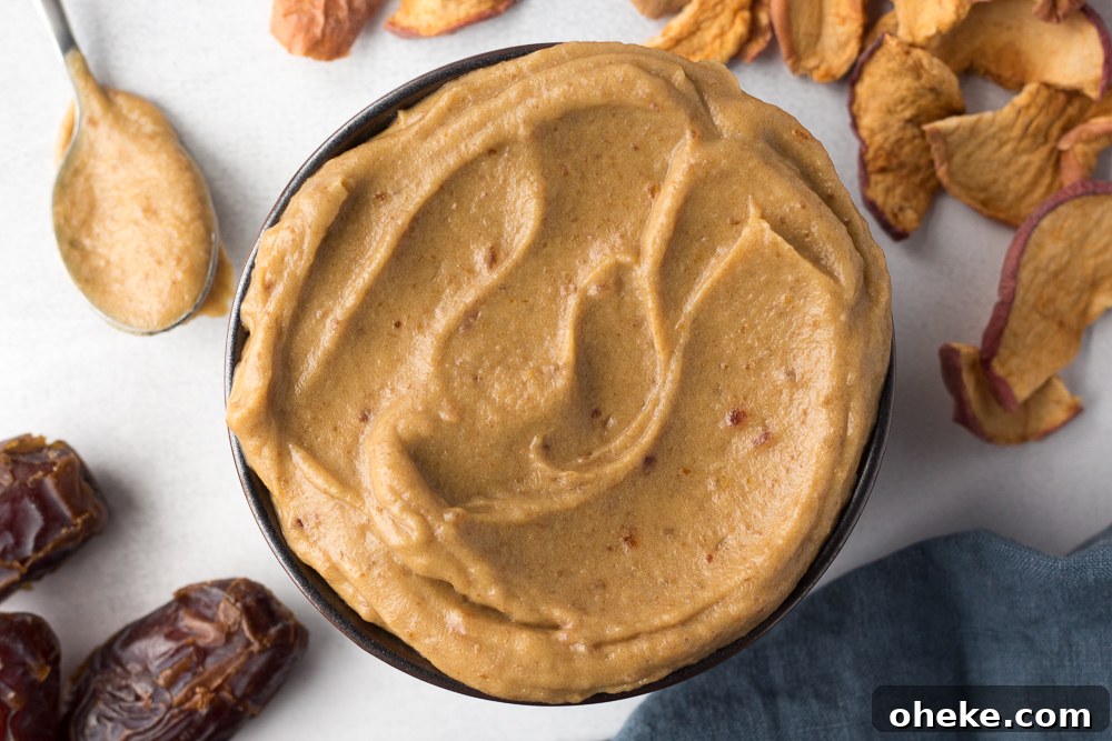 Tahini Date Caramel Dip served in a bowl with a spoon and apple chips by Flora & Vino