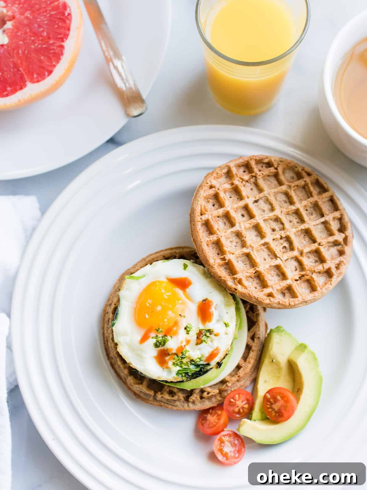 Waffle Breakfast Sandwich Ideas for Quick Morning Meals 5 Two wholegrain waffles, one topped with an over easy egg, spinach, avocado, and hot sauce.