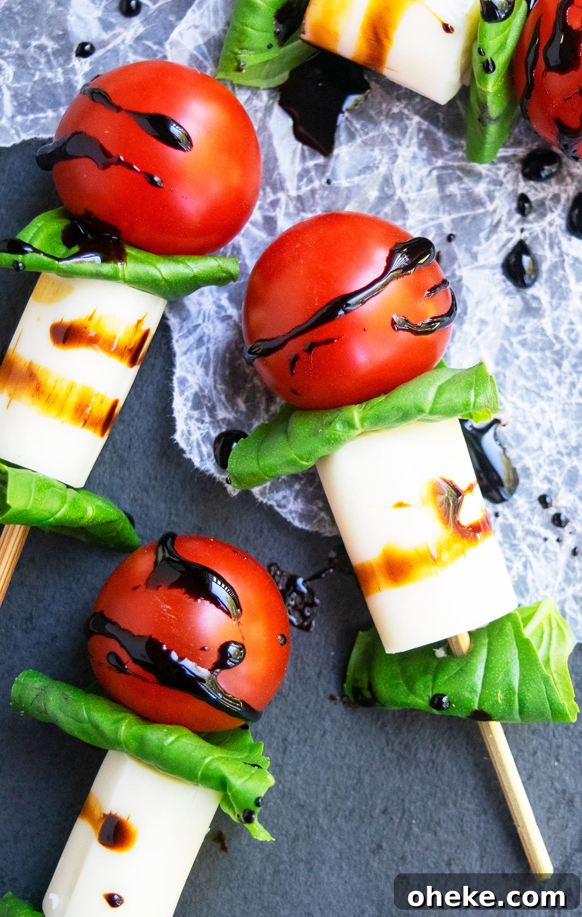 Caprese Skewers on One Pan: Quick Tomato, Basil & Mozzarella Recipe 2 Easy mini caprese skewers with balsamic glaze on charcoal gray dish.