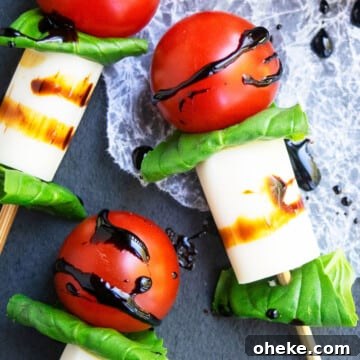 Easy homemade mini caprese skewers or kabobs appetizer with balsamic glaze on charcoal gray dish.