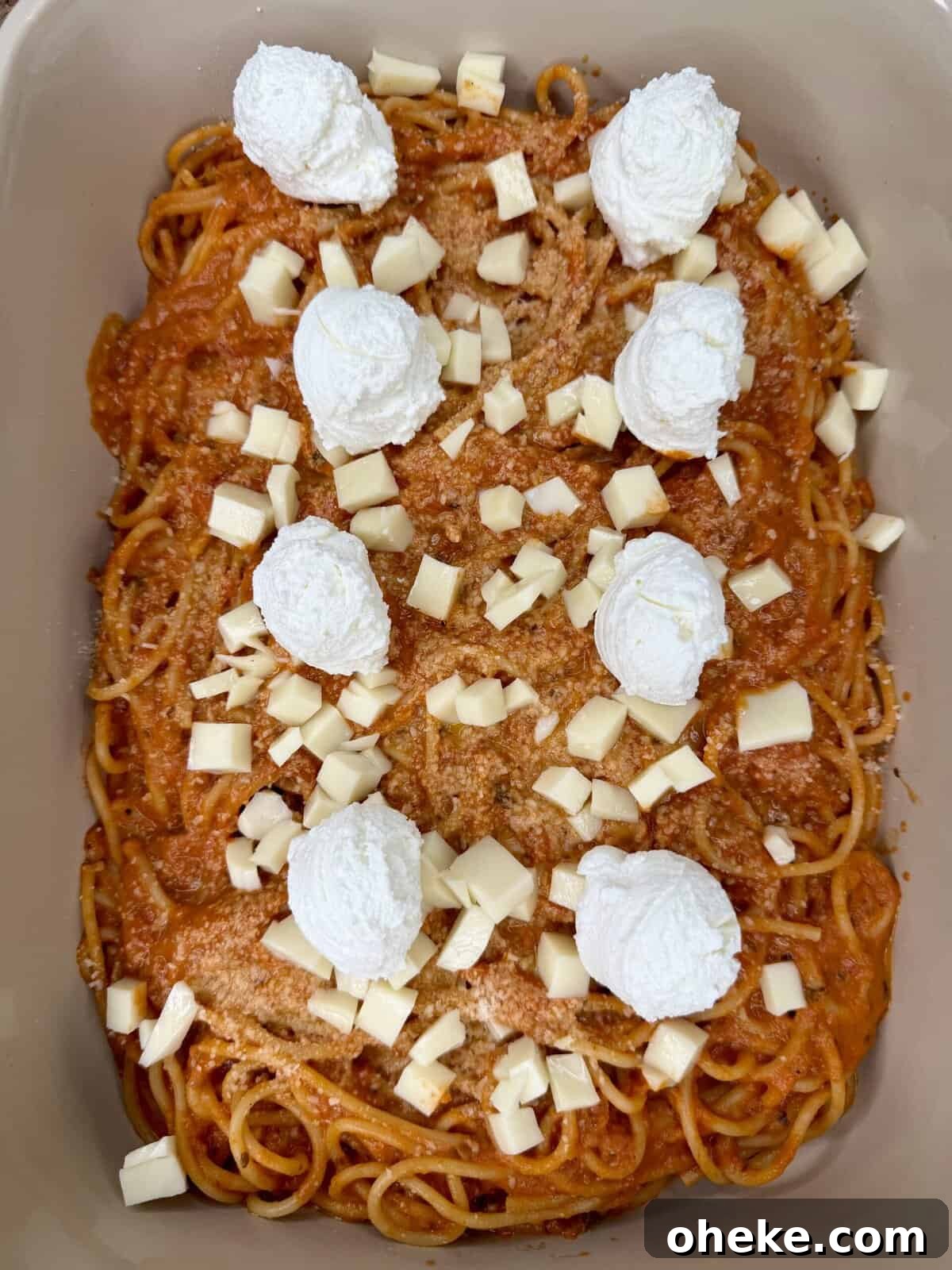 Creamy Italian Baked Spaghetti Recipe — a Tastier Twist on Baked Ziti 10 A baking dish filled with spaghetti in tomato sauce, topped with dollops of ricotta cheese and scattered cubes of mozzarella cheese.