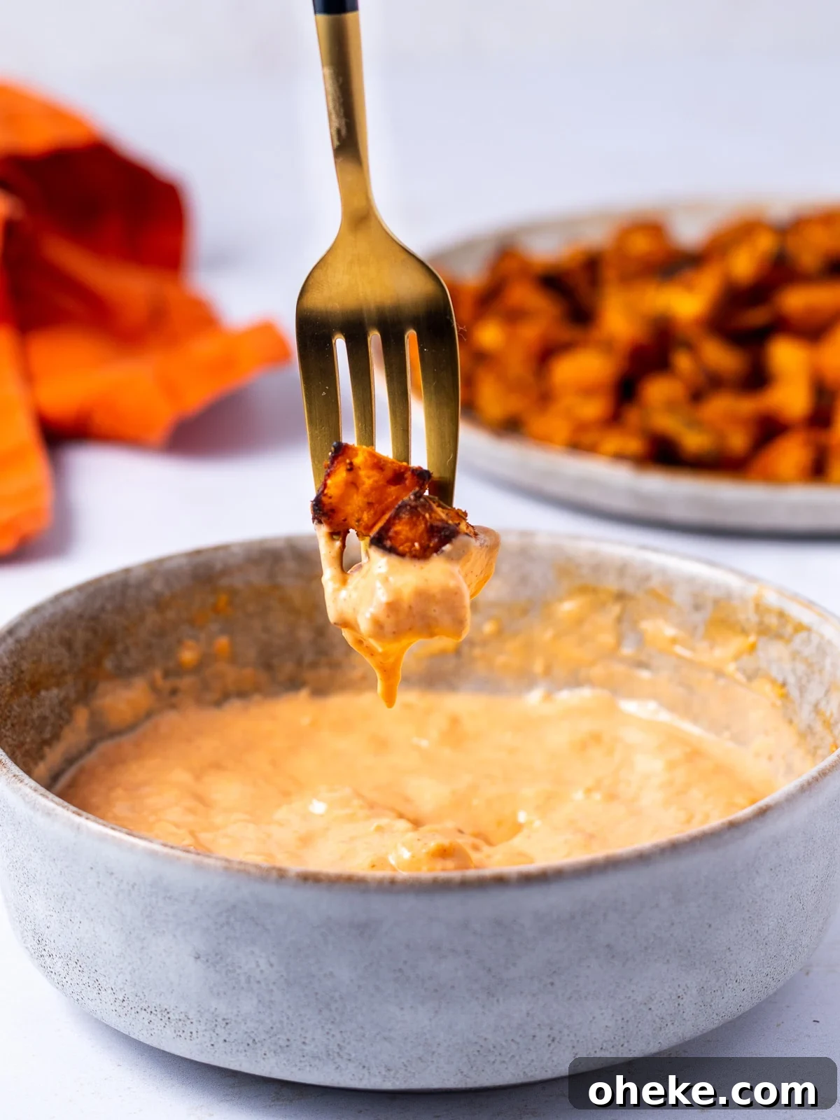 fork with roasted sweet potato cubes dipped in harissa aioli