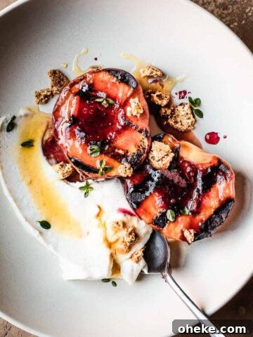 Grilled peaches with creamy cheese and honey in a low bowl with a spoon.