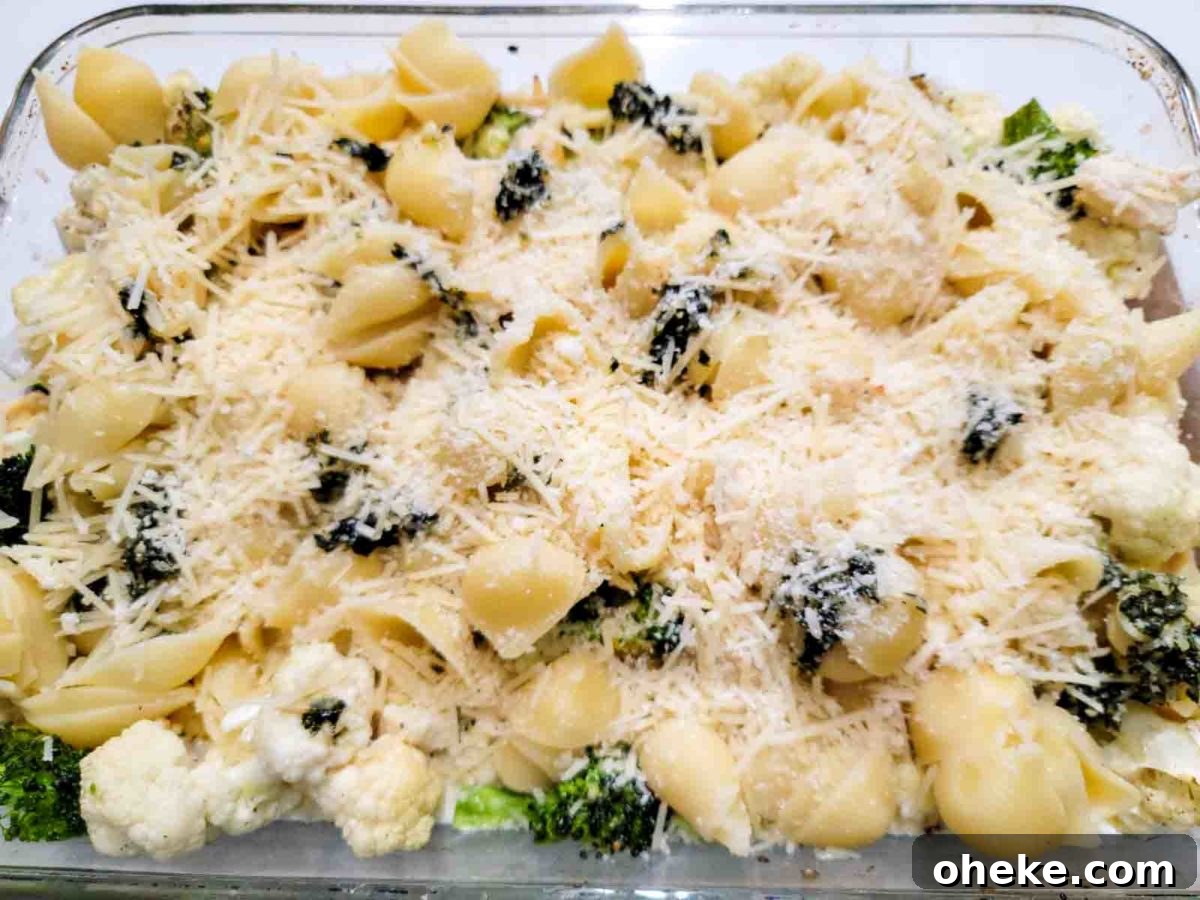 Chicken Broccoli Cauliflower Pasta topped with cheese in a baking dish.