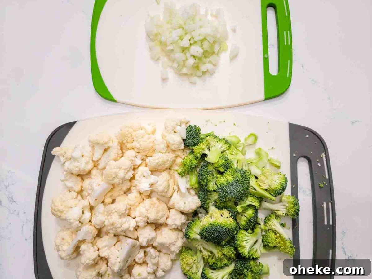 chopped broccoli, cauliflower, and onions on two cutting boards.