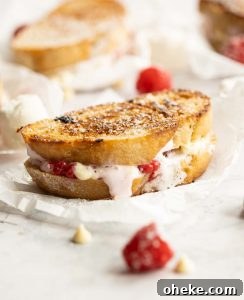 White chocolate raspberry sandwiches sandwich on crumpled parchment paper surrounded by raspberries and white chocolate chips