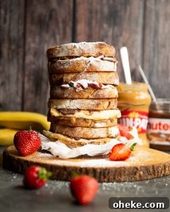 Nutella peanut butter sandwiches 4 sandwiches stacked on each other on wooden board garnished with icing sugar and strawberries