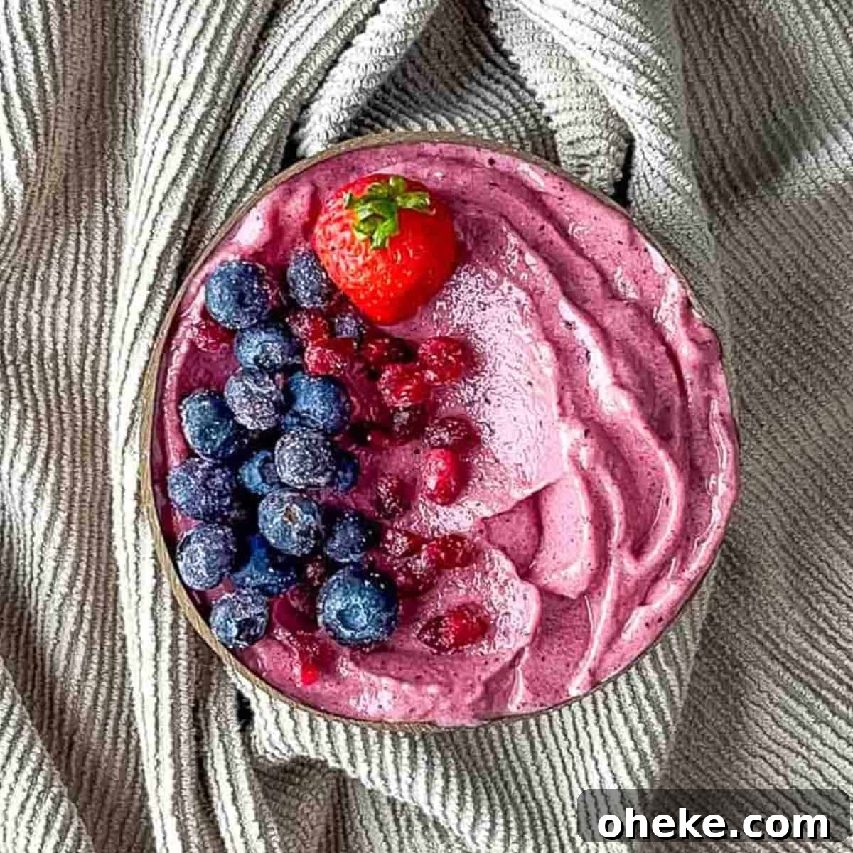 Thick & Creamy Smoothie Bowl Recipe for Spoonable Breakfast 7 A thick pink smoothie bowl artfully topped with frosty blueberries, ruby-red pomegranate seeds, and a bright fresh strawberry, presenting a feast for the eyes.