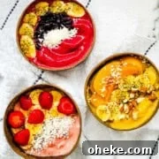Thick & Creamy Smoothie Bowl Recipe for Spoonable Breakfast 9 Three thick smoothie bowls topped with strawberries, bananas, blueberries, peaches, coconut, chia seeds, and almonds.