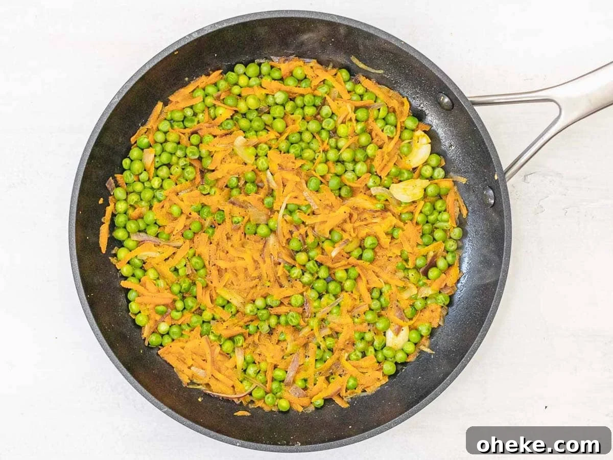 Savory Chickpea Frittata Muffins for Meal Prep 7 black skillet with peas and grated carrots