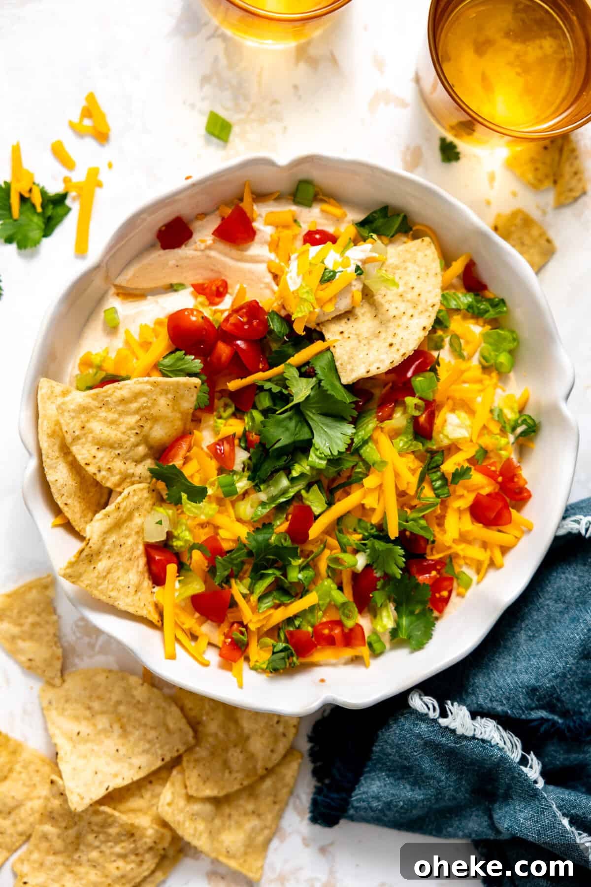 Creamy Layered Taco Dip Recipe for Parties and Game Day 2 Taco dip in a white dish served with tortilla chips.