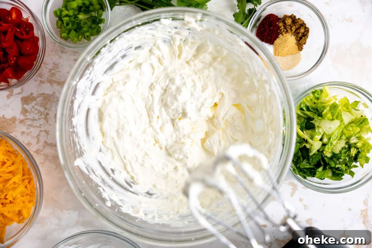 Creamy Layered Taco Dip Recipe for Parties and Game Day 4 Cream cheese and sour cream mixed with hand mixer.