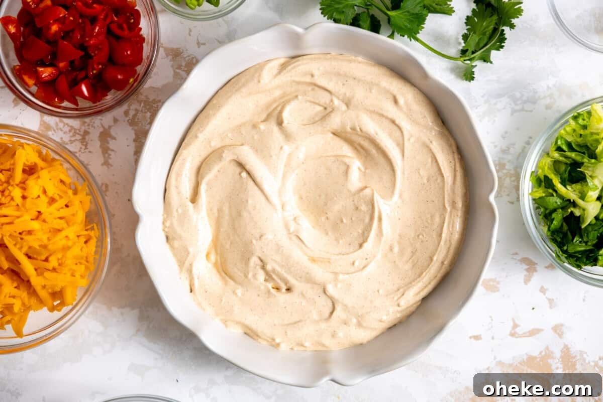Creamy Layered Taco Dip Recipe for Parties and Game Day 6 Taco dip spread in white serving bowl.