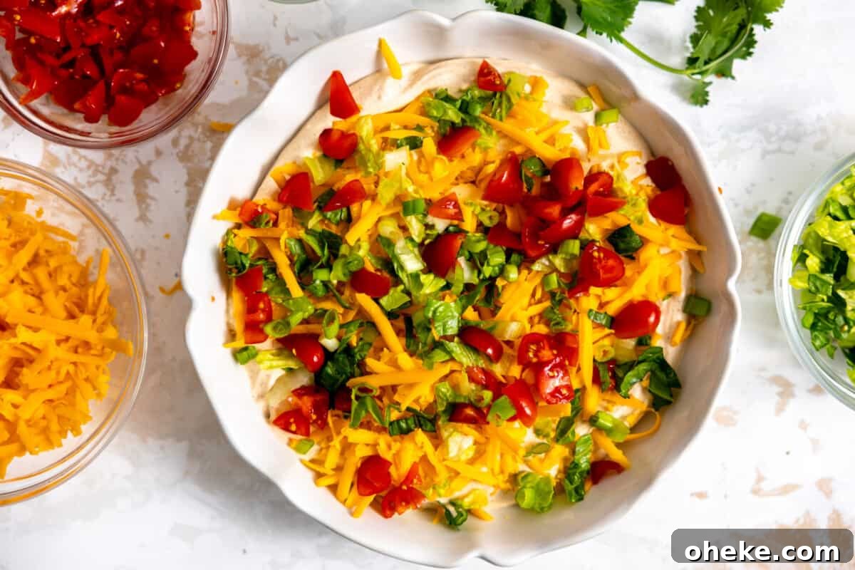 Creamy Layered Taco Dip Recipe for Parties and Game Day 7 Taco toppings added on top of creamy dip.