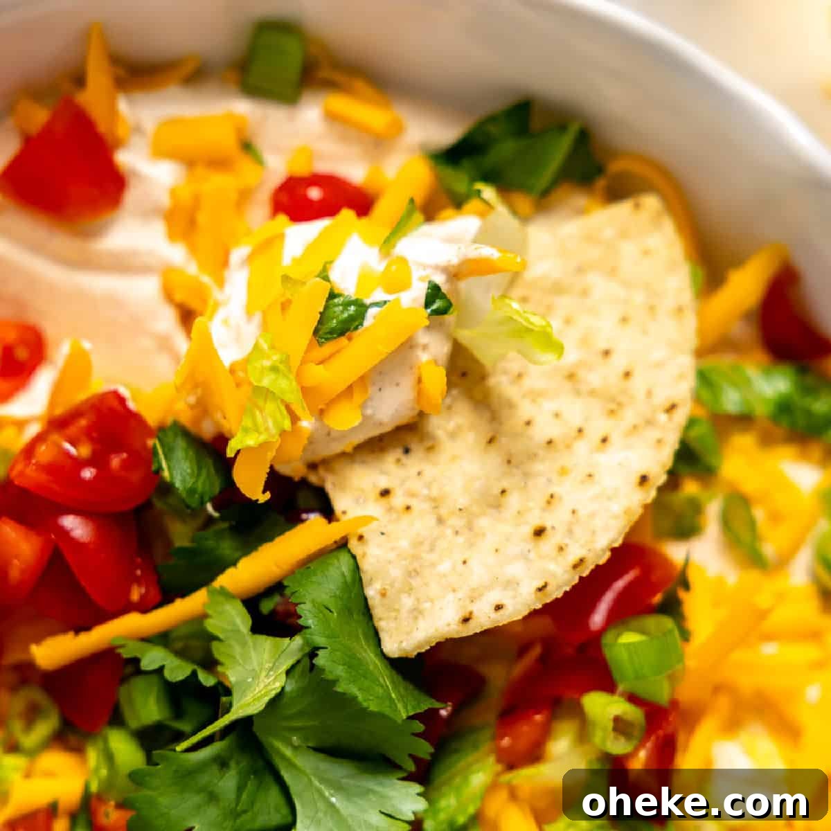 Creamy Layered Taco Dip Recipe for Parties and Game Day 9 Tortilla chip scooping up taco dip.