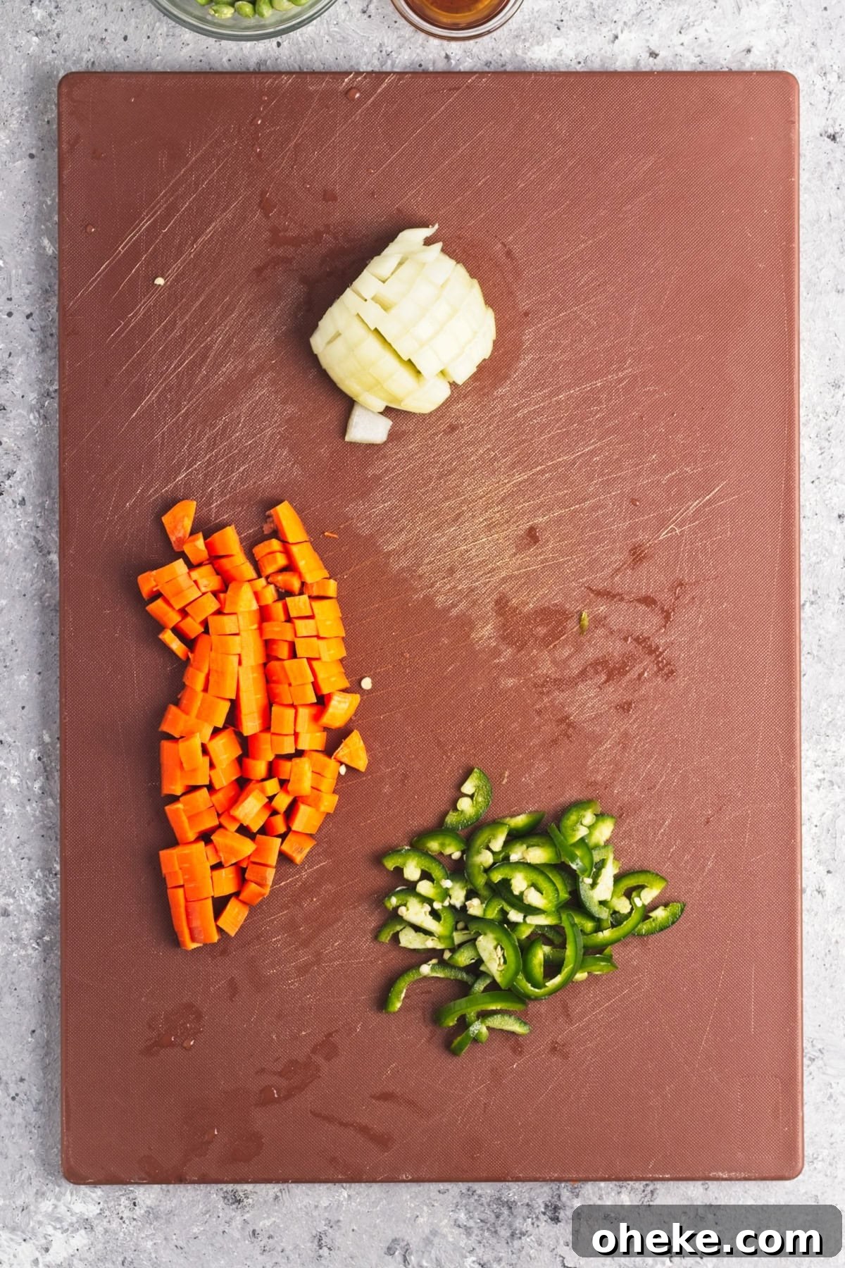 Wok-Seared Pineapple Fried Rice with Shrimp and Cashews 4 An overhead image of cutting carrots, onions, and jalapenos on a chopping board.