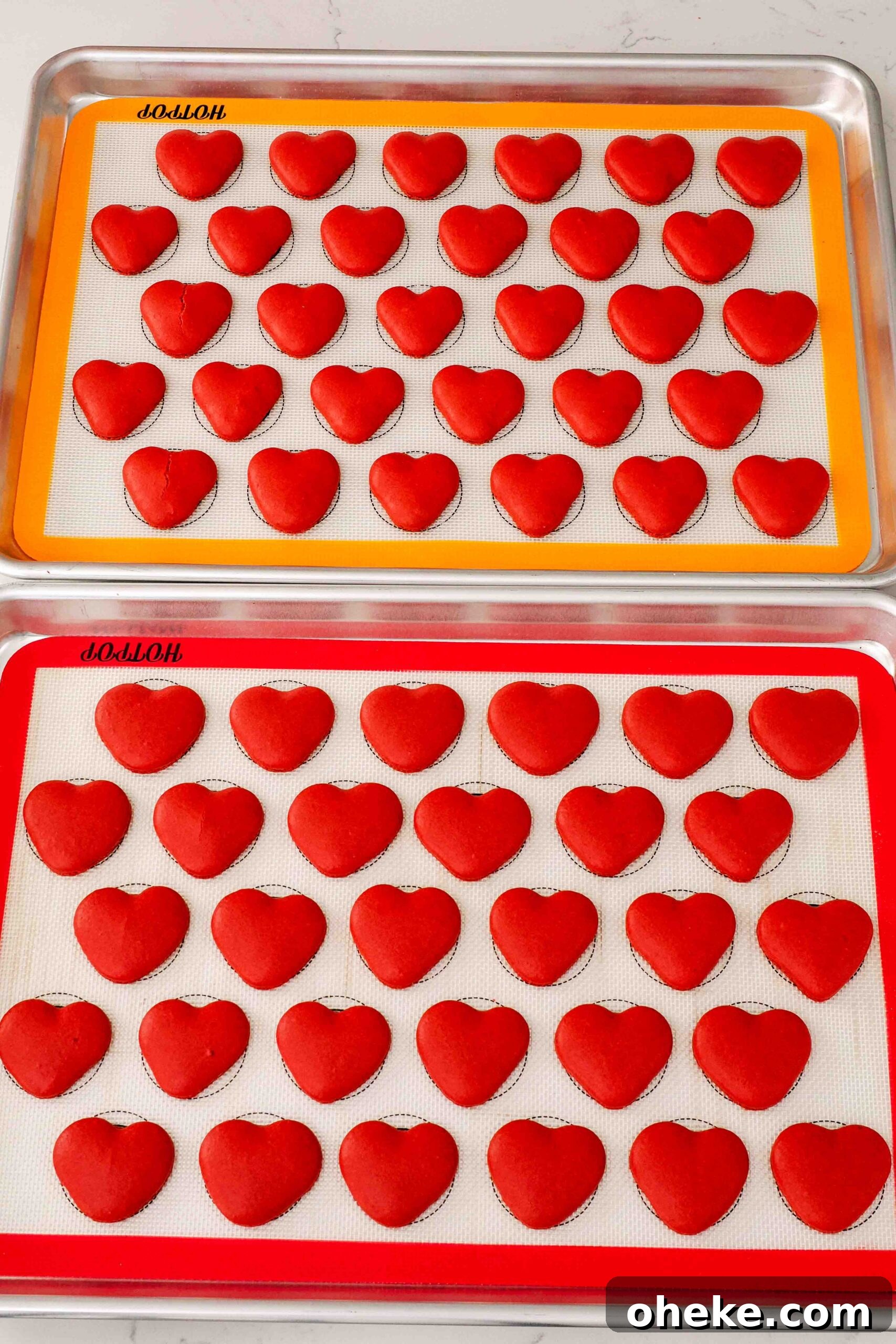 Heart-Shaped Chocolate Raspberry Macarons Recipe 14 Freshly baked heart macarons on silicone macaron mats.
