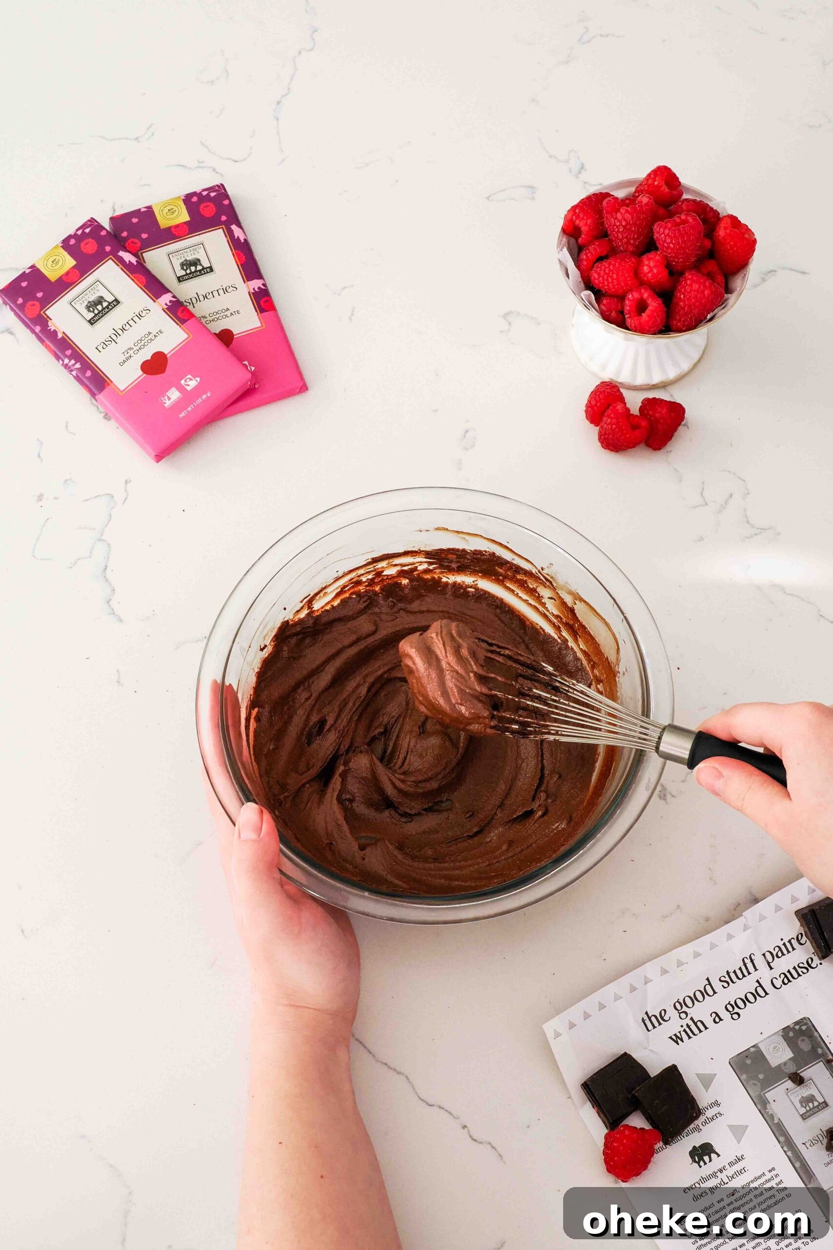 Heart-Shaped Chocolate Raspberry Macarons Recipe 16 A whisk filled with raspberry chocolate ganache hovers over a bowl of ganache.