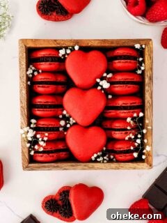 Heart-Shaped Chocolate Raspberry Macarons Recipe 20 A wooden box is filled with red, heart-shaped macarons and baby's breath flowers.