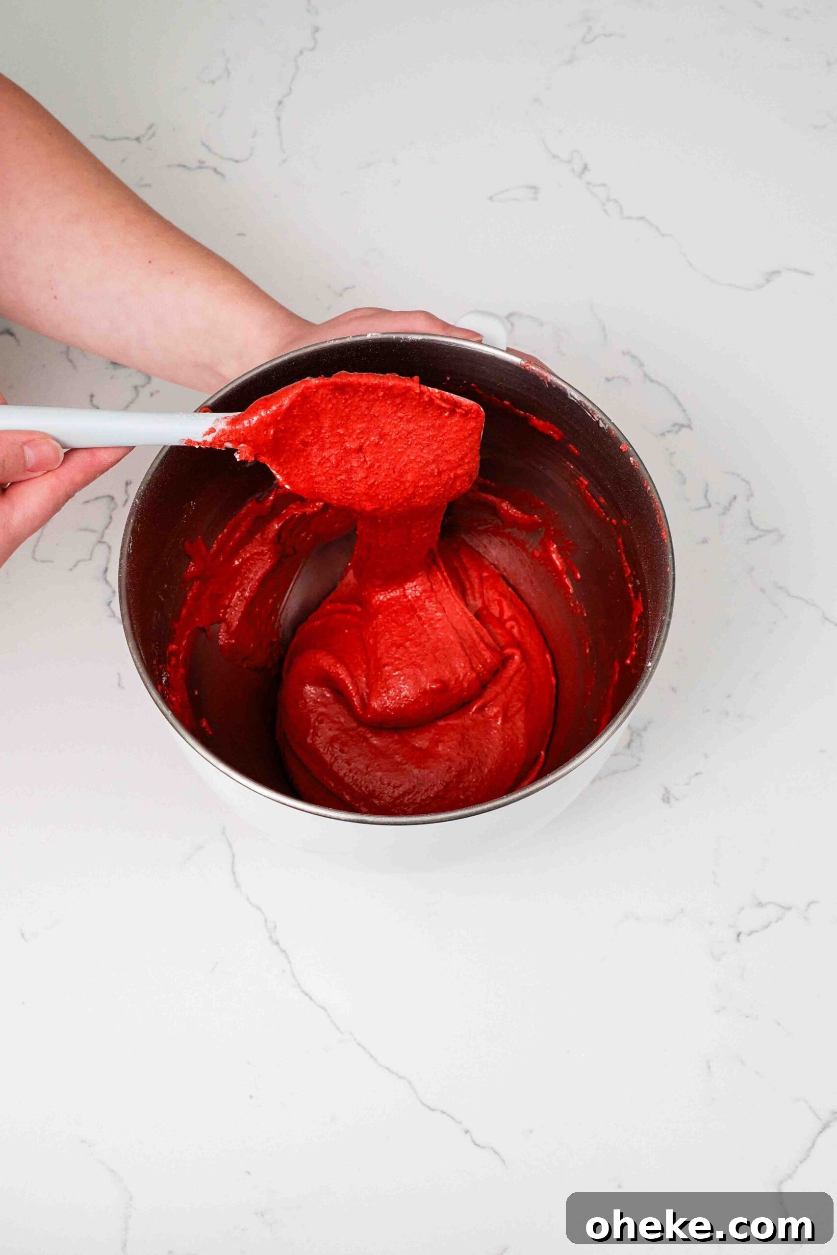 Heart-Shaped Chocolate Raspberry Macarons Recipe 9 Macaron batter trails off a spatula in a long ribbon.