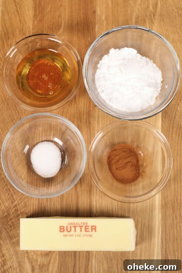 Five bowls on a wooden surface contain honey, powdered sugar, white sugar, cinnamon, and a stick of unsalted butter ready to be whipped into that delicious Texas Roadhouse Butter you're craving.