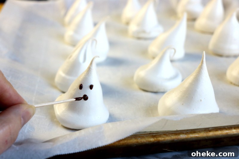 Ghost Meringues Recipe: How to Make Spooky Meringue Cookies 9 After the ghost meringues are hardened, use the melted chocolate chips to decorate the mouth and eyes with a toothpick.