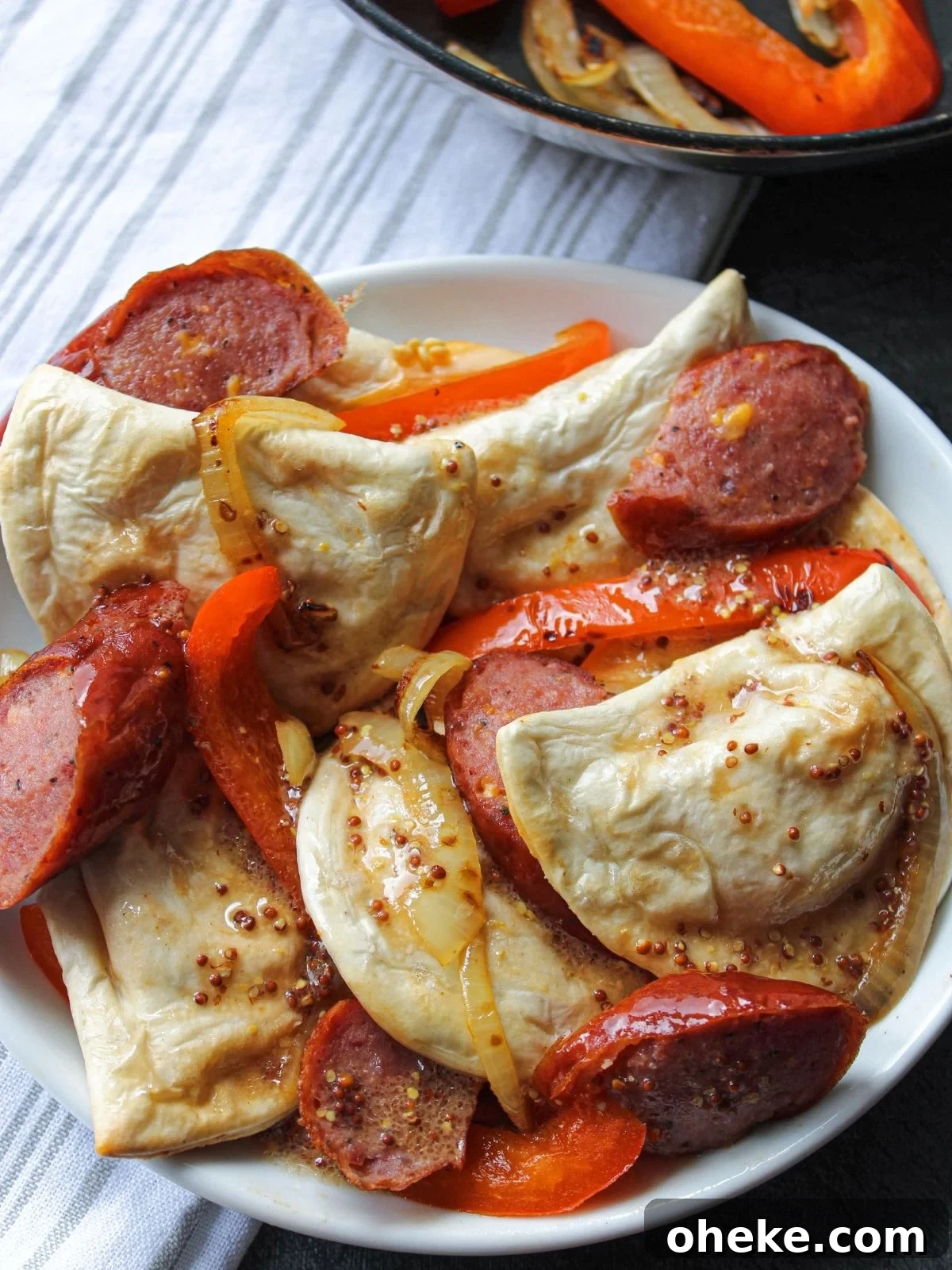 Crispy Air Fryer Pierogies with Kielbasa and Caramelized Onions 2 Air fryer pierogies on a platter with peppers, kielbasa, onion, and mustard vinegar.